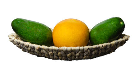 on a white background, a wicker oblong plate with two avocados and grapefruit lie in one lineの写真素材