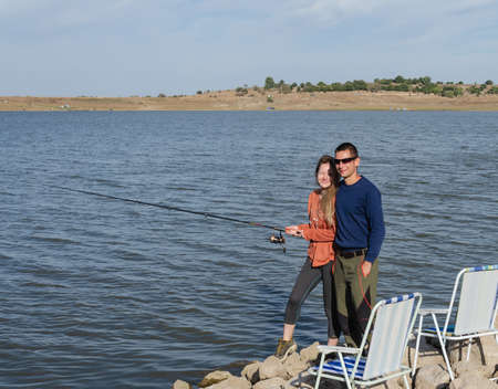 happy guy and girl fishing with a rod on the lakeの写真素材
