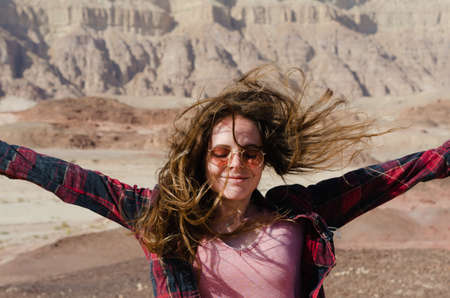 A young model girl with long hair poses for the camera in the red Canyon mountains of Timna National Park in Israelの写真素材