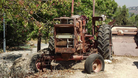 an old brown wheeled agricultural tractor is out of order in the yardの写真素材