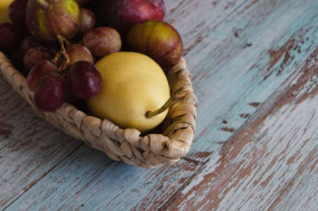 fruit trees on a wicker plate in the form of a boat, which stands on boards in the style of Provence against the wall of a red brick wallの写真素材