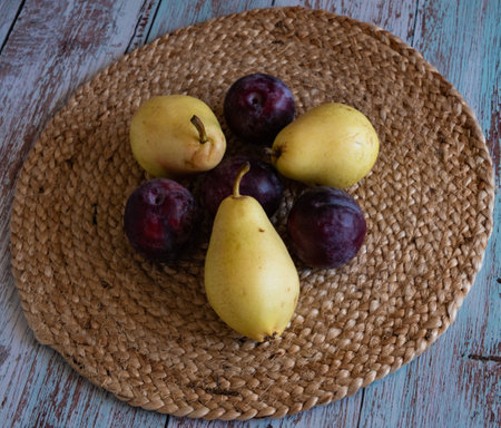 pears and plums lie on wicker napkins on boards in the style of Provence against the wall red brickの写真素材