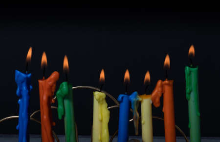 Candlestick with colorful candles on a black background close-up.の写真素材