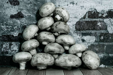 Fresh champignons lie on the table against the background of a brick wall black and white photography close-upの写真素材