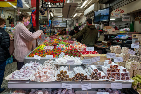 TEL AVIV, ISR - January 25, 2022: Israelis shop at the Carmel Shuk HaCarmel Market in Tel Aviv, Israel. This is a very popular market in Tel Aviv where they sell confectionery as well as fruits and vegetables.のeditorial素材