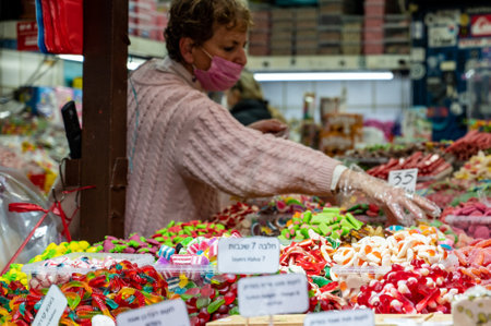 TEL AVIV, ISR - January 25, 2022: Israelis shop at the Carmel Shuk HaCarmel Market in Tel Aviv, Israel. This is a very popular market in Tel Aviv where they sell confectionery as well as fruits and vegetables.のeditorial素材