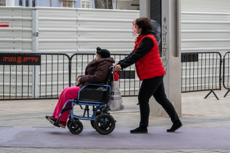Netanya, Israel - February 7, 2022: Elderly grandmother in wheelchair with granddaughter in spring nature. close-up.のeditorial素材