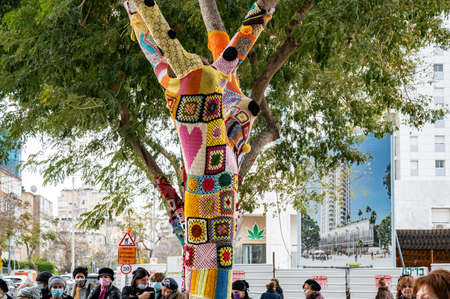 Colorful crochet knit on a tree trunk yarn bombing. Patchwork knitted crochet covered tree for warmth, protection and decoration. high resolutionの写真素材