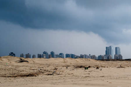 Abandoned sandy wasteland in the distance the city is visible. overcast weather. There are lead clouds in the sky. scenery.の写真素材