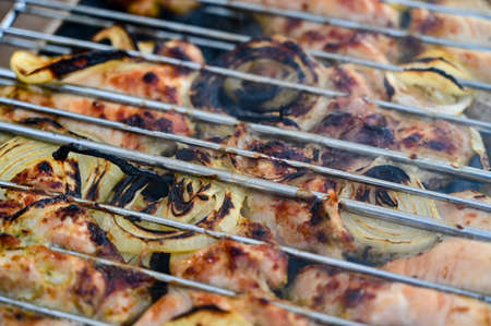 Slices of chicken with array rings are fried on the grill between the lattices squeezed. close up.