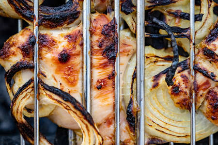 Slices of chicken with array rings are fried on the grill between the lattices squeezed. close up.の写真素材