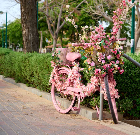 pink bicycle decorated with flowers is left on the street close-up.の写真素材