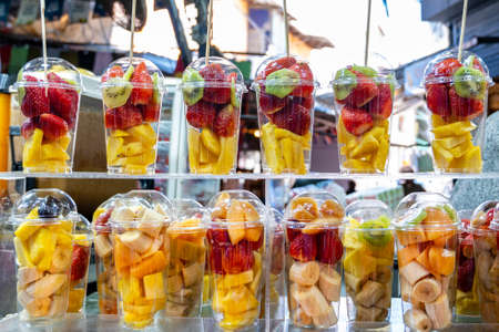 Fruits are harvested and stacked on the counter in the market for squeezing juice on a manual press. Assorted fruit pieces in a transparent glass. close-up.の写真素材
