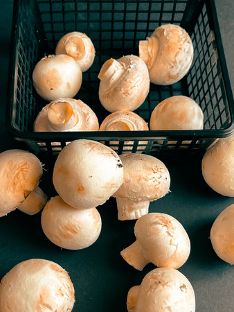 Fresh champignons in a plastic basket on a black background. close-up.の写真素材