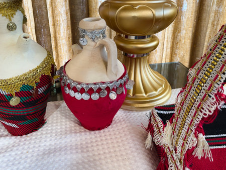 Brass bowls and jugs are covered with red fabric with handmade embroidery. Decorative crockery in the Middle Eastern style. Eastern dishes.の写真素材