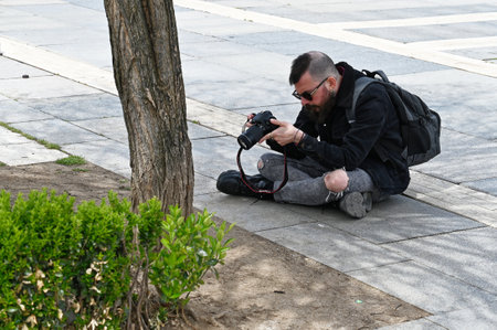 SOFIA, BULGARIA - April 15, 2023: Street a photographer photographs flowers in the center of Sofia. National Palace of Culture. High quality photoのeditorial素材