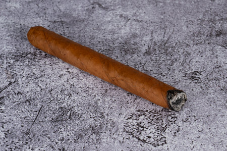 A cigar made of tobacco leaves lies on a gray marble table. High quality photoの写真素材