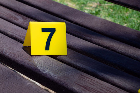 One yellow crime scene marker on a wooden bench. High quality photoの写真素材