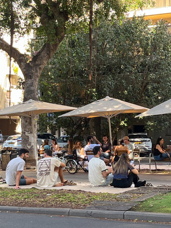 Tel Aviv, Israel, November 21, 2025: Visitors are sitting on outdoor carpets near a cafe in the Hatsafon Hayashan - South Part area. High quality photoのeditorial素材
