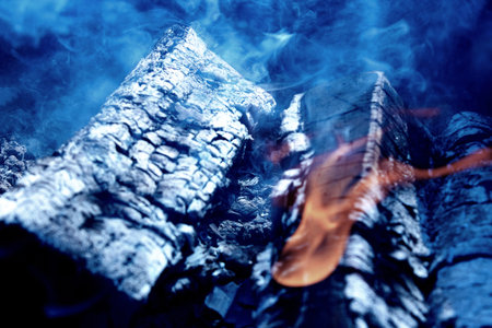 Blurred birch burnt wood in the grill or on the fire. Extinguished flames and a lot of smoke.