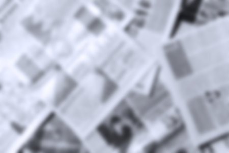 Monochrome blurred background of newspapers close up.