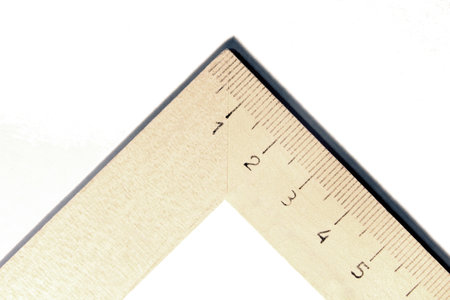 Corner of a measuring wooden school square with symmetrical sides on a white surface. Right angle of...