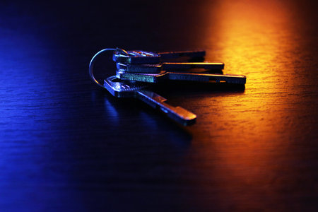 The keys to the apartment are on the table. Dark background with blue and orange glow.の写真素材