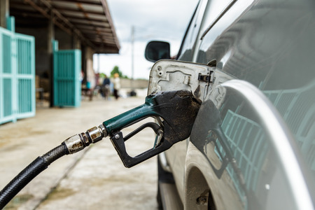 dirty gas pump nozzle in the fuel tank of a pick-up truck