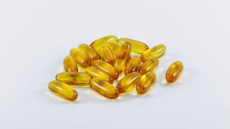 Detail of yellow gel pills with medicine on white backgroundの写真素材