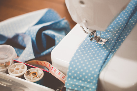 Sewing machine with many sewing utensils on a wooden table