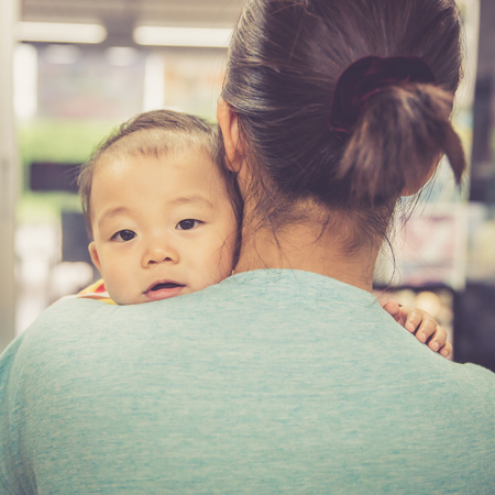 Asian boy crying on mother shoulder, warm retro styleの写真素材