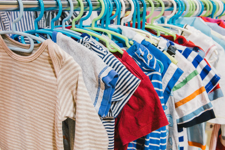 Kid clothes of different colors on plastic hangerの写真素材