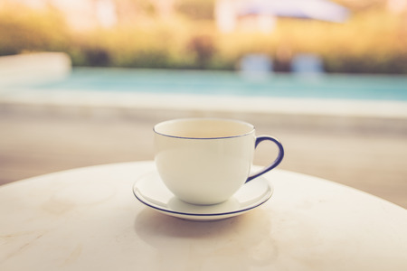 Cup of coffee on the table near swimming pool in the morningの写真素材