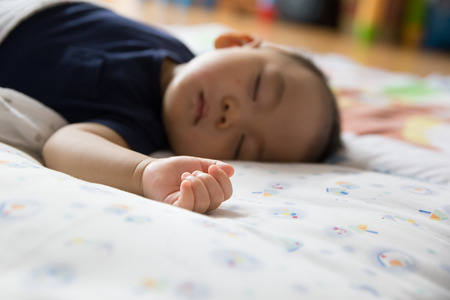 Baby asleep on bed, focus at handの写真素材