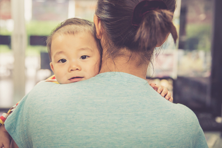 Asian boy crying on mother shoulder, warm retro styleの写真素材