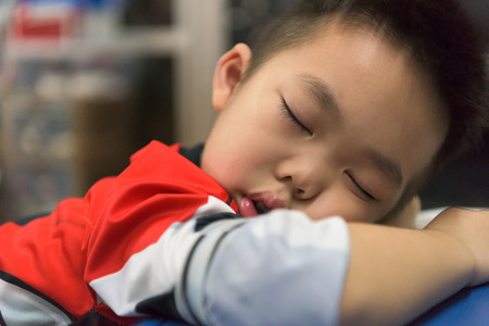 Portrait of a asian schoolboy sleeping on his blue deskの写真素材