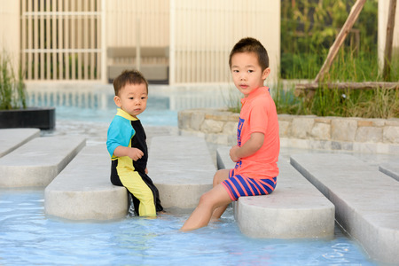Two happy kids in swimsuit, relaxing in the pool.の写真素材