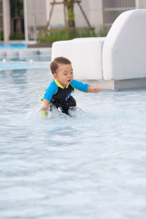 Asian boy wearing swimsuit having fun at the swimming poolの写真素材