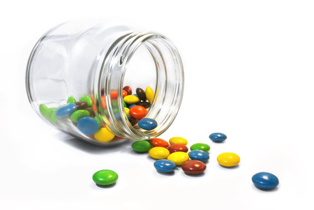 color candy in clear glass pot bottle on white backgroundの写真素材