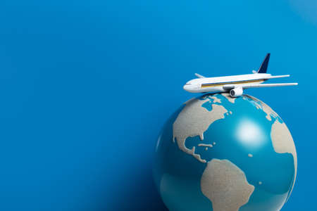 white airplane toy model with global world on blue background in airline business for travel tour international conceptの写真素材