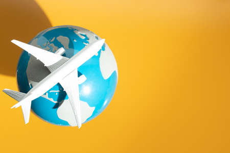 airplane toy with global world map on yellow background in transportation business for travel tourist international concept, summer season holiday vacation, logistic import exportの写真素材