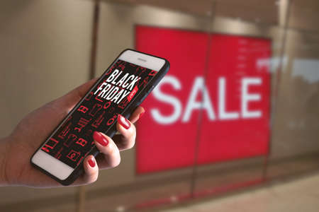 girl hand holding network online smartphone device application for buy product in black friday shopping discount sale season event weekend in supermarket store conceptの写真素材
