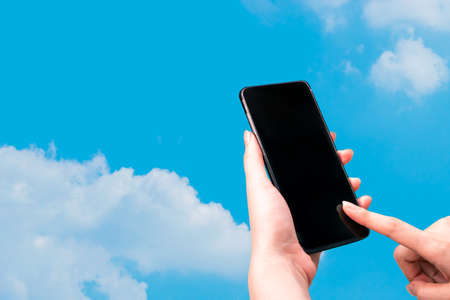 girl hand finger touch on screen smartphone device with cloud sky background for connecting to social network internet digital with data safety securityの写真素材