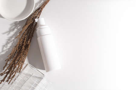 top view beauty spa medical skincare concept, cosmetic spray cream bottle packaging with white decor background and dried herb flowerの写真素材