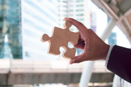 businessman holding the jigsaw puzzle toy in business vision for leadership winner concept, financial risk tradingの写真素材