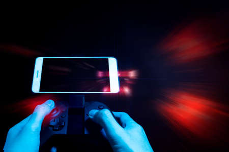 gamer boy with hand holding the joystick controller electronic for playing game with online network connection  technology device in smartphone applicationの写真素材