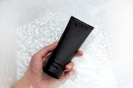 mockup of beauty men cosmetic makeup black bottle lotion product with skincare healthcare concept on water drop backgroundの写真素材