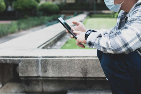 teen boy using smartphone device for online network technology internet;  man use mobile in public parkの写真素材