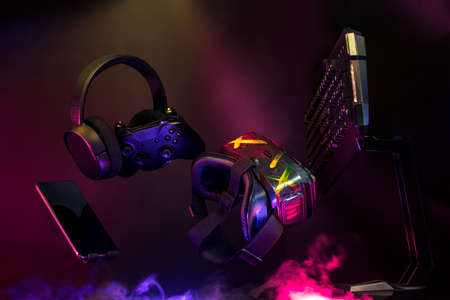 gamer devices for playing game by joystick with computer headphone and mouse on neon glow, gaming and esports challenge, streaming online, tournament conceptの写真素材