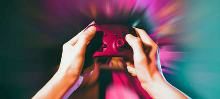 gamer playing the online game with joystick controller in neon glow dark cyberpunk room, gaming and e-sports challenge tournament streaming, streamer with analog device in living houseの写真素材